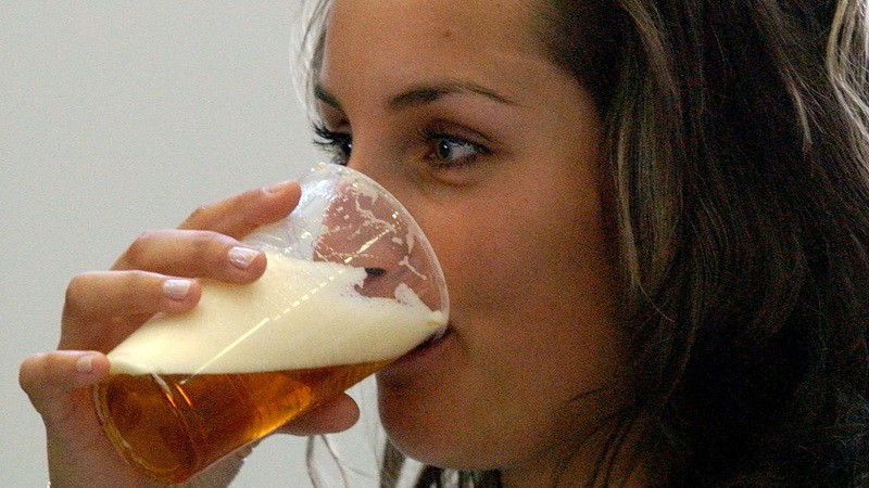 Žena pije pivo z plastového pohára